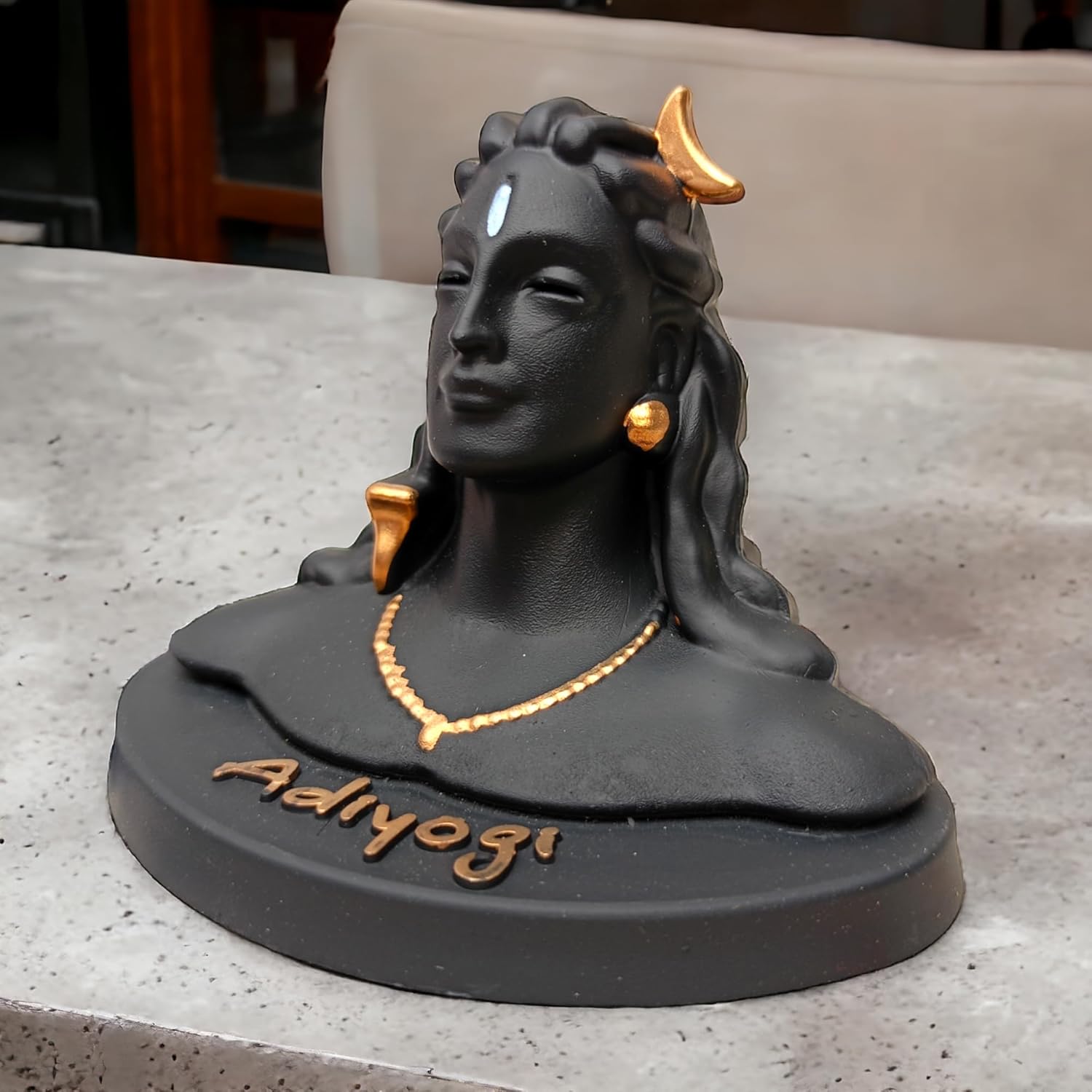 Black and gold statue of a deity on a gray surface